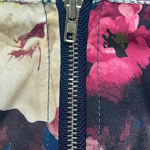 Detailed macro view of the silver metal zipper on the floral print woven fabric garment