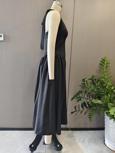 Detail view of the elegant black halter neck dress showing the pleated skirt texture
