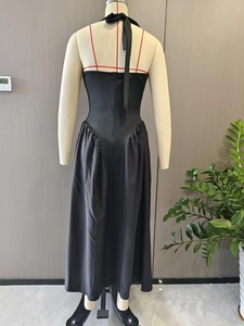 Detail view of backless black halter dress featuring rear zipper and elegant pleated hem