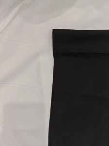 Close-up of neat stitching and plain weave texture on the hem of a black V-neck dress