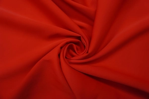 Detailed view of red textile fabric texture with elegant draping and smooth glossy finish