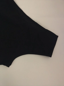 Close-up detail of the smooth black fabric and precise stitching on the wide-leg jumpsuit