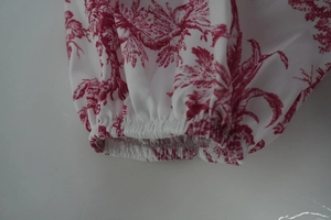 Détail du poignet élastique sur robe à fleurs blanche avec motifs toile rouges