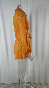 Detail of orange shirt and high-waist shorts set with cotton-linen texture on mannequin