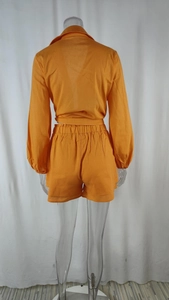 Rear view of orange two-piece set featuring long-sleeved shirt with tie-back hem and shorts
