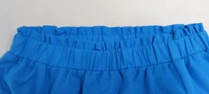 Detail of blue elastic waistband with visible stitching on textured casual trousers