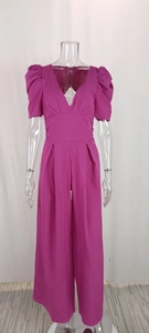 Detailed view of magenta V-neck jumpsuit with puff sleeves and cinched waist on mannequin