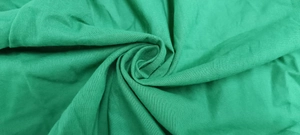 Macro shot of green textured cotton linen fabric showing the soft weave and drape