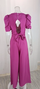 Detail view of the back cutout and large bow on a fuchsia V-neck jumpsuit for women