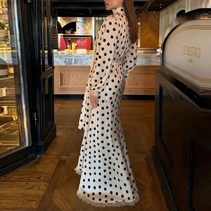 Dettaglio di un abito bianco a pois con orlo a frange e maniche lunghe in ambiente di lusso