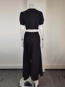 Rear view of black two-piece set featuring short crop top and high waist wide leg pants