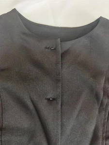Detail view of round neckline and handmade buttonholes on black elegant two-piece set