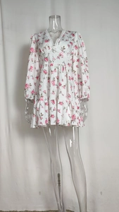 Close-up of V-neck lace trim and pink floral rose pattern on short white dress