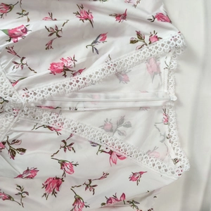 Close-up of V-neckline with delicate white lace trim and floral rose print detail