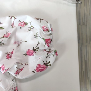 Detail showing white floral dress fabric with pink roses, elastic cuffs, and lace trim
