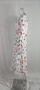 Détail d'une robe longue fleurie blanche avec manches bouffantes et fente latérale