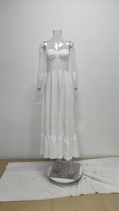 Détail d'une robe blanche à fines bretelles avec ourlet volanté et corsage plissé