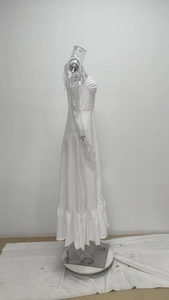Détail de la robe longue blanche montrant les plis délicats et l'ourlet à volants doux