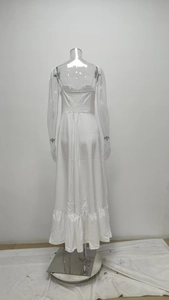 Détail de l'ourlet à volants et du dos smocké élastique sur une robe longue blanche sans manches