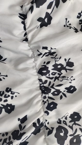 Vue détaillée du fronçage élastique sur le tissu blanc imprimé floral de la robe vintage