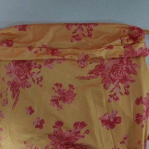 Detail of yellow floral satin fabric showing smooth texture and pink flower patterns