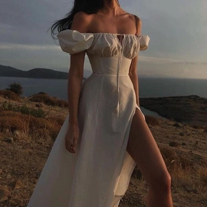 Detail of white off-shoulder dress featuring puff sleeves and a high side slit lace-up design