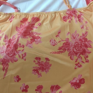 Close-up of vibrant yellow floral print dress with thin straps and ruffled neckline