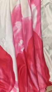 Detailed view of vibrant red and pink floral print fabric with smooth draped texture
