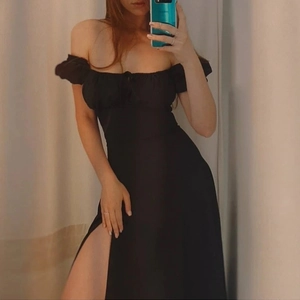 Detail of off-the-shoulder puff sleeves and lace-up front on a black slit dress