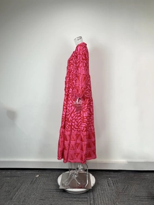 Detail of multi-tiered maxi dress featuring vibrant pink and red abstract wave pattern