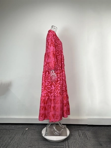 Detail of multi-tier boho maxi dress featuring pink abstract floral print and long sleeves