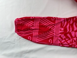 Detail of elastic cuff with pink geometric swirl print on red V-neck long dress