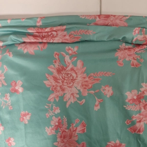Detail of floral print fabric in teal with pink flowers and a silky smooth texture