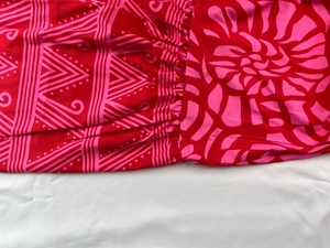 Close-up of red fabric featuring pink floral patterns and detailed pleating craftsmanship