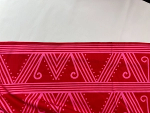 Detailed close-up of red fabric featuring pink geometric patterns on a V-neck dress