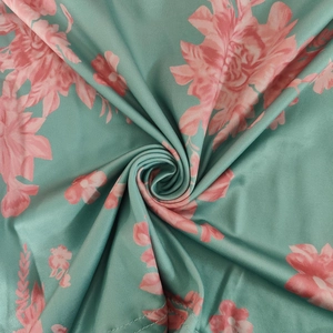 Close-up of glossy satin fabric with pink floral patterns on green dress detail