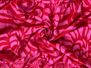Close-up of vibrant red floral print fabric with elegant layered ruffle details