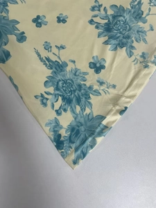 Detailed close-up showing blue floral print on beige fabric with premium rolled hem stitching