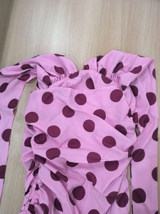Detail of pink polka dot dress with V-neckline and side drawstring ruching details