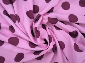 Macro shot of soft pink chiffon fabric with dark purple polka dots in a spiral drape