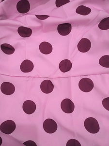 Detailed seam of a pink polka dot chiffon dress showing clean stitching and fabric texture