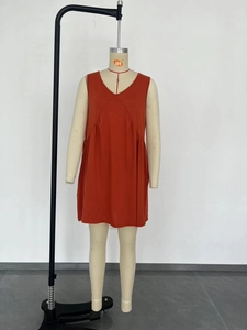 Detail view of the V-neckline and waist pleats on an orange sleeveless summer dress