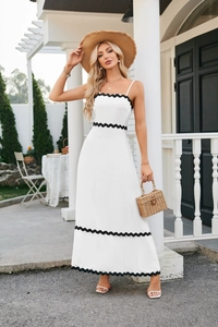 Detailed view of a white maxi dress with black scalloped trim and thin straps