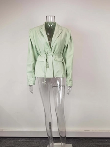Détail d'un blazer vert clair à col en V avec ceinture à la taille et poches à rabat chic