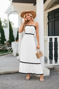 Detail of white midi dress with black wavy scalloped trim and textured fabric