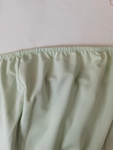 Gros plan sur la taille élastique froncée et le tissu côtelé fin d'une robe vert menthe