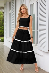 Dettaglio del crop top senza maniche e gonna lunga a balze con bordo a onde bianco
