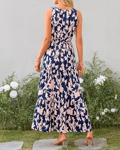 Back view of a sleeveless navy blue floral maxi dress with tiered skirt in a garden setting