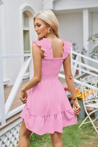Detail of pink sleeveless ruffled mini dress with elastic smocked bodice and textured fabric