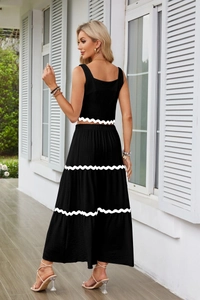 Dettaglio del completo nero a due pezzi con finiture bianche smerlate su top e gonna a balze